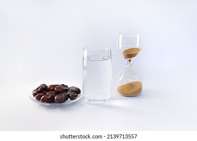 Dry pitted dates fruits, glass of water and hourglass on white background. Ramadan fasting concept. Traditional Muslim food before Iftar during Holy month of Ramadan Kareem. Selective focus on dates.