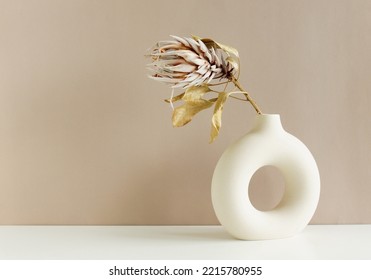 Dry Protea flower in modern ceramic vase on beige table .Copy space.Minimal Scandinavian neutral trendy colors interior decoration .