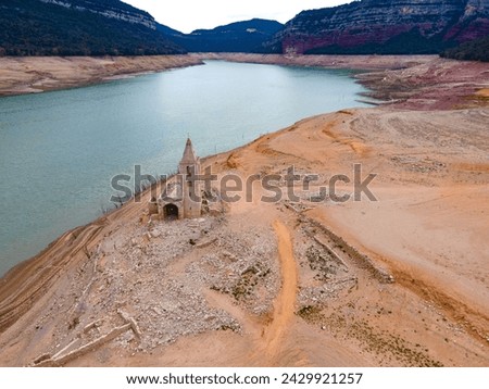 dry reservoir with an abandoned church on the shore. Dried reservoir Sau in Catalonia, Spain. drought. Climate change drought land and water in reservoir