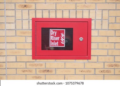 Dry riser inlet box red on brick wall for emergency fire services water connection for hose brigade engine at shopping mall retail park