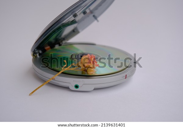 dry rose and CD player. dry rose lies on a\
portable compact disc\
player