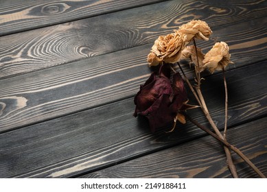 Dry rose flowers on the wooden table background close up. Top view.