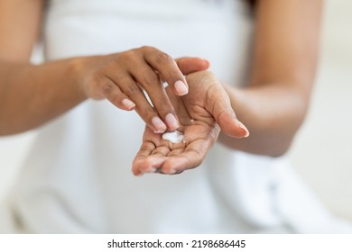 Dry Skin Remedies. Unrecognizable African American Female Applying Moisturizing Cream On Hands, Young Black Woman Rubbing Nourishing Lotion To Palm, Selective Ficus, Cropped Image, Closeup