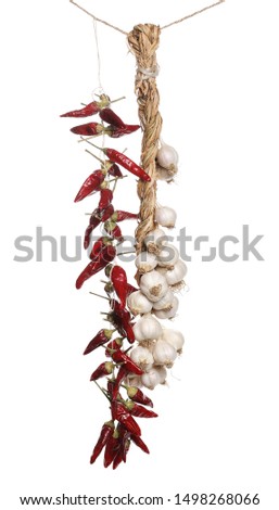Dry spicy peppers and garlic hung by string, isolated on white background