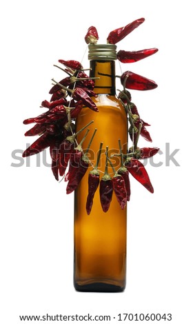 Dry spicy peppers hung by string and  brown glass bottle with tequila brandy isolated on white background