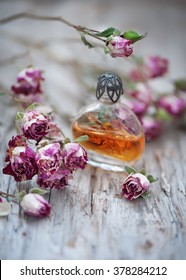 Dry tea roses and vintage perfume bottle on the old wood background