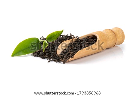 Dry tea in wooden spoons with green leaves, isolated on white background.