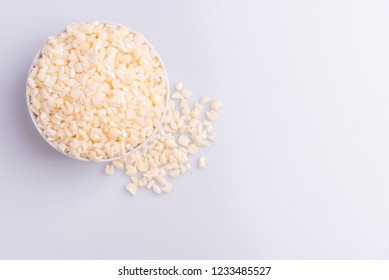 Dry uncooked white corn ingredient for Brazilian dessert sweet canjica / mungunza in a white bowl, white background, isolated, top view, soft light. Festa Junina Party Brazilian Culture Concept Image.