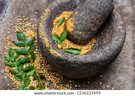Dry whole coriander being crushed to powder in a traditional kitchen using vintage grinder stone mortar and pestle, Kerala India. Home made Indian spices for hot and spicy  gravy curry, cuisine, dish.