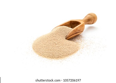 Dry yeast in wooden scoop on white background