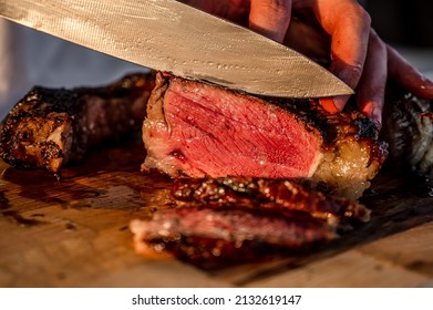 Dryaged raw Tomahawk steak on wooden background with vegetables for grilling. Premium beef grilling on a kamado grill. Bone-in ribeye steak on wooden cutting board grilling on coals. Premium steak cut