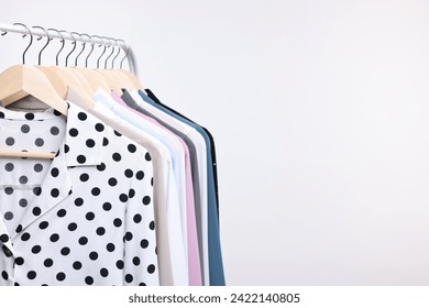 Dry-cleaning service. Many different clothes hanging on rack against white background, space for text