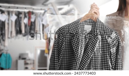 Dry-cleaning service. Woman holding hanger with coat in plastic bag indoors, space for text. Banner design