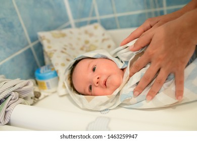 drying of the child after a bath. bathing newborn. Cute newborn girl, a boy in a towel after a bath with his mother's hands dryly and gently rubs the body