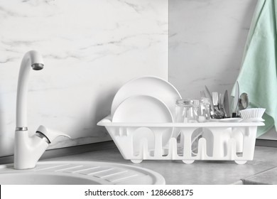 Drying Rack With Clean Dishes, Glasses And Cutlery Near Sink In Kitchen