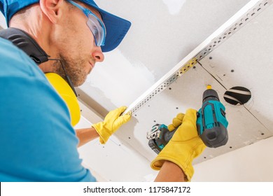 Drywall Ceiling Construction. Caucasian Contractor Worker With Power Tool Building Drywall Elements.