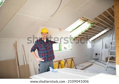 drywall worker with yellow safety helmet works on building site in a house