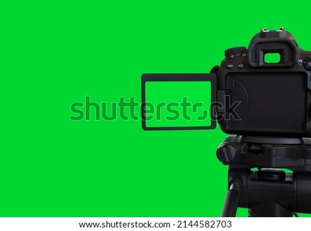Dslr camera with empty screen on the tripod, isolated on green background. Green screen camera.