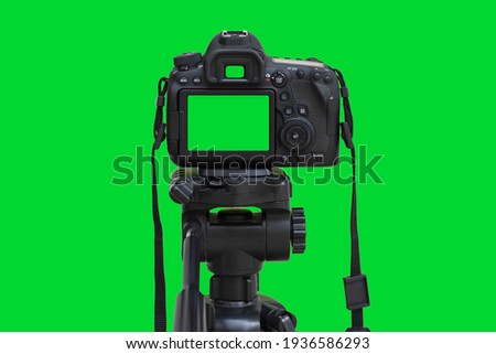 Dslr camera with green screen on the tripod isolated on green background. Green screen camera