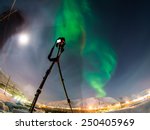 DSLR Camera on tripod shooting amazing green aurora borealis (northern lights) in moonlit night