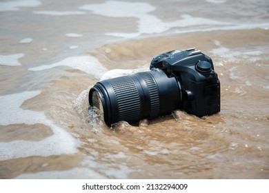 DSLR camera with telephoto lens on a beach it wet from water sea wave when travel and test using in the extreme environment demo waterproof by photographer - Shutterstock ID 2132294009
