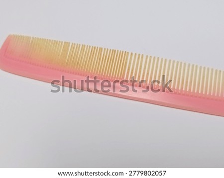 Dual-width pink plastic styling comb isolated on a plain background for daily haircare and detangling.
