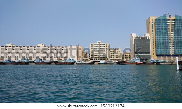 DUBAI CREEK, UAE - 2019. Skyline view of Dubai\
Creek with traditional boat taxi called abra docked. The creek\
divides city into two sections - Deira and Bur Dubai. Goes to Souk\
souqs gold & spices