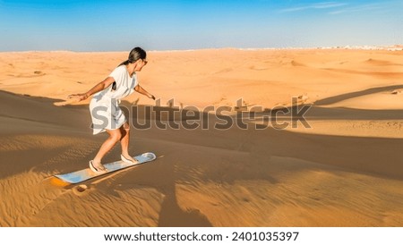 Dubai desert sand dunes, an Asian woman on Dubai desert safari, United Arab Emirates vacation, woman on vacation in Dubai sandboarding at the sand dunes of Dubai 