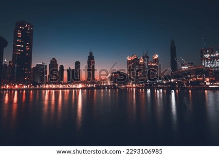 Dubai downtown at night, beautiful glowing lights from the towers reflected in the water, amazing nighttime cityscape
