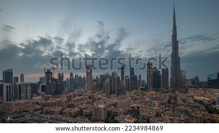 Dubai Downtown panorama day to night transition timelapse with tallest skyscraper and other towers view from the top after sunset in Dubai, United Arab Emirates. Lights turning on.