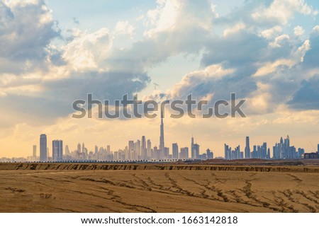 Dubai Downtown skyline with desert sand, United Arab Emirates or UAE. Financial district and business area in smart urban city. Skyscraper and high-rise buildings at sunset.