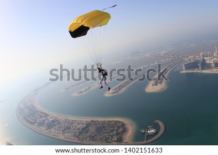 Dubai dream.Yellow extreme skydiving activity fun people on Dubai palm Jumeirah. Skydive Dubai jump travel. Yellow fun parachute jump. Summer  outdoor sky activity. Big goal