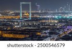 Dubai Frame with Zabeel Masjid mosque illuminated at night timelapse. Aerial view from above. Skyscrapers on background. The Frame is an architectural landmark in Zabeel Park.