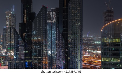 Dubai International Financial Center Skyscrapers Aerial Night Timelapse. Illuminated Towers And Traffic On Intersection View From Above