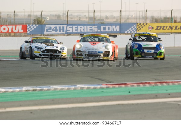 DUBAI - JANUARY 14: Aston\
Martin Vantage, Porsche 997 and BMW MIni fighting for positions\
during the 2012 Dunlop 24 Hour Race at Dubai Autodrome on January\
14, 2012.