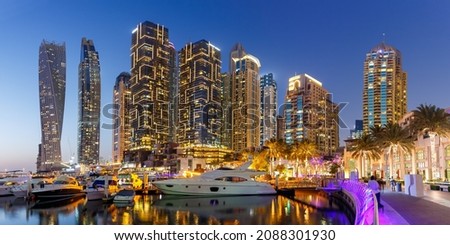 Dubai Marina and Harbour skyline architecture wealth luxury travel with yacht boat at night panorama in United Arab Emirates modern