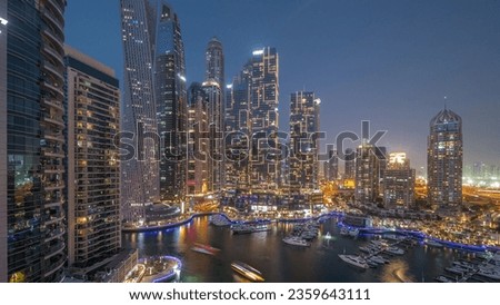 Dubai marina tallest skyscrapers and yachts in harbor aerial night panoramic timelapse after sunset. View at apartment buildings, hotels and office blocks, modern residential development of UAE