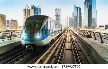 Dubai metro train on rails at background of skyscrapers. Famous outdoor subway Red Line.