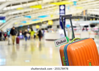 Dubai. Orange suitcase with label at airport.