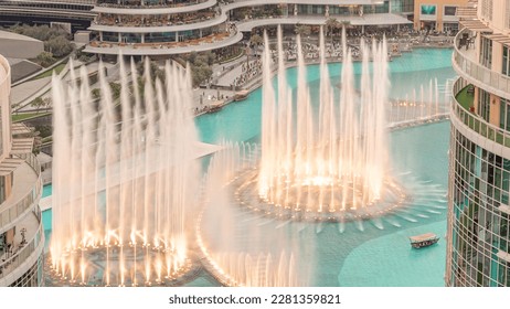 Dubai singing fountains with walking area around aerial . People watching show near shopping mall during sunset