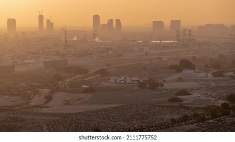 Dubai Skyline With Villa Houses And Construction Site Of New Towers On A Background Orange Sky Aerial Timelapse During Foggy Sunrise. Desert Road With Empty Area From Above