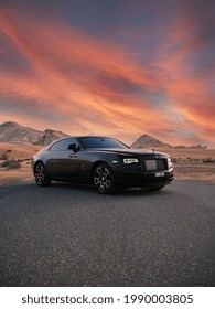 DUBAI ,UAE - 01-01-2021: Rolls Royce Wraith luxury car in Dubai desert at sunset, mountains.