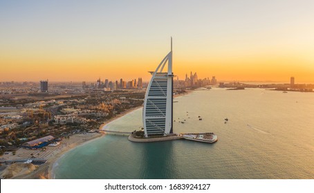 Dubai, UAE - 03/25/2020 : Aerial view of Burj Al Arab Jumeirah Island or boat building with downtown skyline. Financial district in urban city. Skyscrapers at sunset.