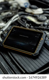 DUBAI / UAE - 07 05 2018: Mechanic Uses A Tablet To Diagnose Faults In An Auto Repair Shop. Heavy Duty, Tough Tablet Like Ipad, Tools Cars In Background