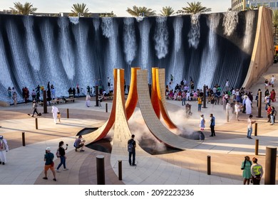 Dubai, UAE, 09.12.2021. Expo 2020 Dubai Water Feature, monumental fountain in Jubilee Park with people playing in the water fire inspired sculpture with smoke in the middle.