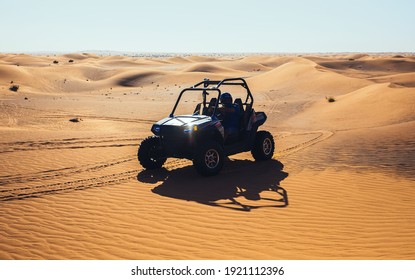 Dubai, UAE - 12.13.2014: Beautiful ride of quad buggy car at sand dunes with sun flare on headlight, male driver has fun at sports vehicle extreme safari tour 
