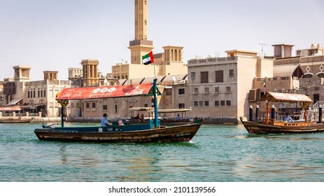 Dubai, UAE, 24.09.21. Traditional Arabic "Abra" wooden boat on Dubai Creek, Old Dubai and Al Fahidi Historical District buildings and mosque in the background.