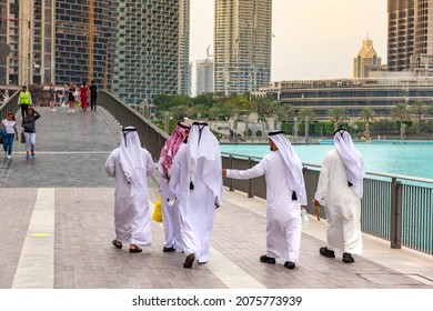 DUBAI, UAE - APRIL 5, 2020: Arabic men wearing traditional white clothes walking in Dubai downtown, United Arab Emirates