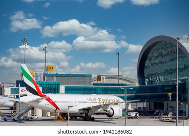 DUBAI, UAE - CIRCA 2021: Emirates Airline Airplanes parked on Dubai Airport, on cloudy sky background.
