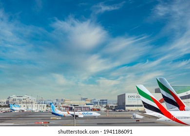 DUBAI, UAE - CIRCA 2021: DUBAI, UAE - CIRCA 2021: Emirates Airline and FlyDubai Airline Airplanes parked on Dubai Airport, on cloudy sky background.